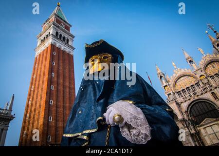 VENEDIG, ITALIEN - 28. JANUAR 2018: Eine Person mit einem typischen blauen Kostümkleid und einer Gesichtsmaske auf dem Markusplatz, während des Karnevals von Venedig Stockfoto