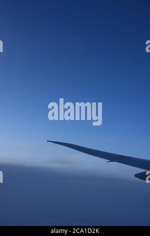 Flugzeugflügel mit Dämmerung und tiefblauem Himmel auf dem Flug nach Japan. Stockfoto