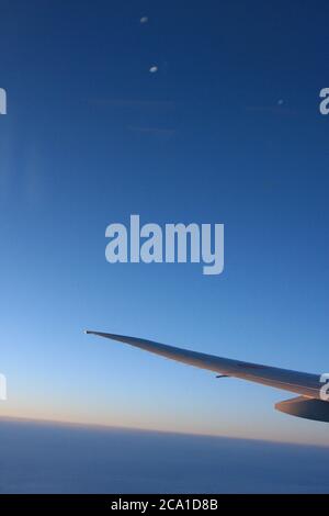 Flugzeugflügel mit Dämmerung und tiefblauem Himmel auf dem Flug nach Japan. Stockfoto