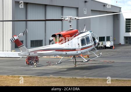 Sidney, British Columbia, Kanada 03. Aug. 2020 - EIN Hubschrauber von VIH Helicopters, der an einem Wassereimer (links) befestigt ist, hebt sich vom Shell Aerocenter am Victoria International Airport ab, um Waldbrände zu bekämpfen. Die jüngste heiße Trockenheit hat in der gesamten Provinz zu einem starken Anstieg der Waldbrände geführt. Der Hubschrauber taucht den Eimer in einen nahe gelegenen See und lässt ihn dann über die Feuerzone fallen. Don Denton/Alamy Live News Stockfoto