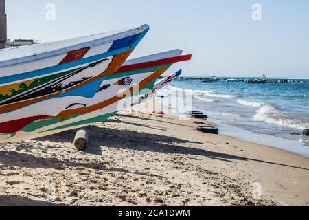 Typische Fischerboote in Yoff Dakar, Senegal, genannt Pirogue oder Piragua oder Piraga. Bunte Boote, die von Fischern am Strand in Afrika benutzt werden. Stockfoto