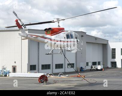 Sidney, British Columbia, Kanada 03. Aug. 2020 - EIN Hubschrauber von VIH Helicopters, der an einem Wassereimer (unten) befestigt ist, hebt sich vom Shell Aerocenter am Victoria International Airport ab, um Waldbrände zu bekämpfen. Die jüngste heiße Trockenheit hat in der gesamten Provinz zu einem starken Anstieg der Waldbrände geführt. Der Hubschrauber taucht den Eimer in einen nahe gelegenen See und lässt ihn dann über die Feuerzone fallen. Don Denton/Alamy Live News Stockfoto