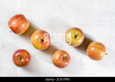 Tischansicht, sechs glänzende Äpfel (kiku-Sorte) auf weißem Arbeitsbrett Stockfoto