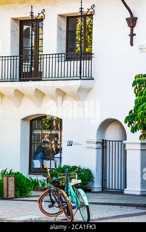 Zwei farbenfrohe Fahrräder parkten vor den Internationalen Sprachzentren in einem charmanten Gebäude mit spanischen Akzenten in Santa Barbara, CA, USA Stockfoto