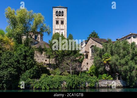 Mittelalterlicher Turm und altes Kloster unter grünen Bäumen unter blau schlaue auf der kleinen Insel San Giulio am See orta im Piemont, Norditalien. Stockfoto