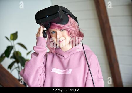 Hipster teen Mädchen mit rosa Haar tragen vr Headset halten Controller Blick auf Kamera. Stockfoto
