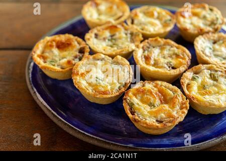 Brasilianische Gastronomie. Käse und getrocknete Fleischpasteten mit Rucola in handgefertigter Schale auf Holztisch. Stockfoto