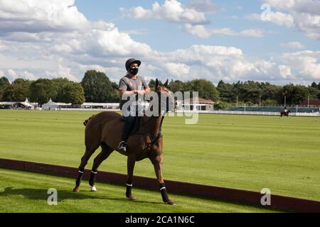 Egham, Großbritannien. August 2020. Ein Bräutigam mit Gesichtsbedeckung zum Schutz vor Coronavirus reitet ein Pferd entlang der Seite eines Polofeldes während eines Cartier Queens Cup 2020 Liga-Phase-Match zwischen Next Generation und Segavas im Guards Polo Club in Windsor Great Park. Next Generation gewann das Spiel 11:9. Kredit: Mark Kerrison/Alamy Live Nachrichten Stockfoto