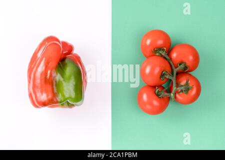 Kreatives Layout aus Pfeffer und Tomate auf buntem grün-weißem Hintergrund. Minimales Sommerkonzept. Zutaten für Salat. Stockfoto