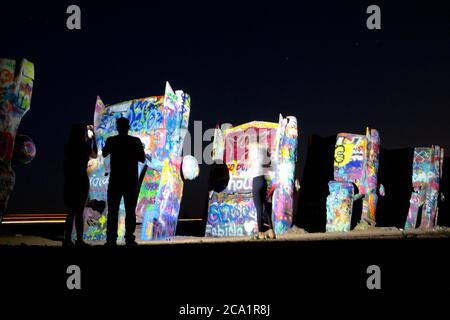 Amarillo, Texas, USA. Juli 2020. 31. Juli 2020, Amarillo, Tx. Die umgedrehten Autos in einem West Texas Feld auf der Cadillac Ranch, die von der Kunstgruppe Ant Farm geschaffen und von Stanley Marsh III finanziert wurden, leuchten unter dem im Juli zunehmenden Mond. Quelle: Ralph Lauer/ZUMA Wire/Alamy Live News Stockfoto