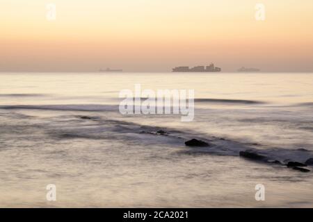 Frachtschiff am Horizont, Morgendämmerung, Bewegungsunschärfe, Landschaft, Seestück, Durban, KwaZulu-Natal, Südafrika, Umhlanga Rocks Strand, Reisen, Transport, schön Stockfoto