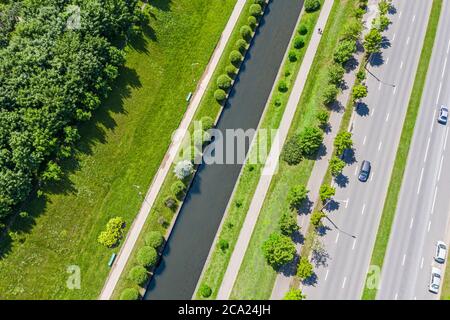 Vorstadtlandschaft mit grünen Bäumen, Rasen und Wasserkanal in der Nähe der Stadtstraße. Luftaufnahme von oben in sonnigen Sommertag Stockfoto