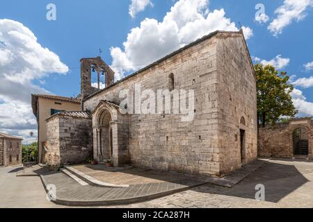 Nahaufnahme einer alten römischen Steinkirche in San Quirico D'Orcia, unter einem sommerlichen blauen Himmel mit geschwollenen Wolken Stockfoto