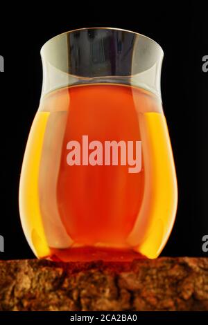 Exquisiter Cognac in einem speziellen Glas auf einem Holzständer auf schwarzem Hintergrund. Nahaufnahme Stockfoto