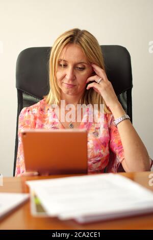 Reife Frau sitzt im Büro mit Tablet Stockfoto