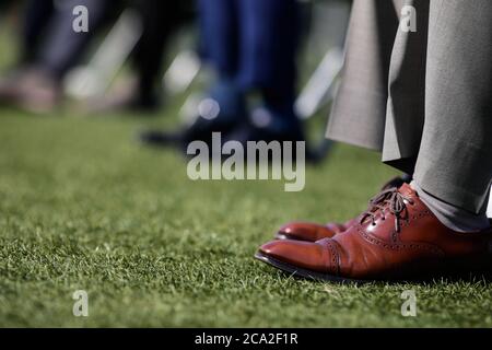 Details mit den Schuhen eines Mannes während einer Veranstaltung auf dem Rasen eines Stadions. Stockfoto