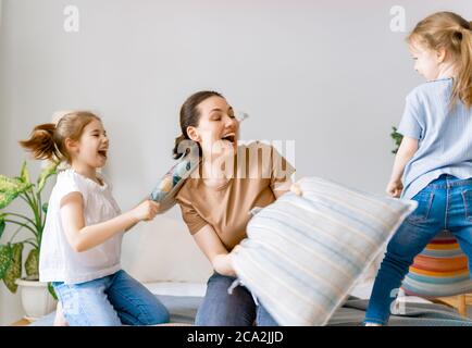 Glückliche, liebevolle Familie! Die Mutter und ihre Kinder kämpfen zu Hause auf dem Bett mit Kissen. Stockfoto