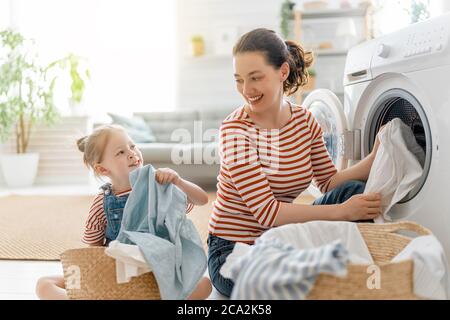 Schöne junge Frau und Kind Mädchen kleinen Helfer haben Spaß und Lächeln, während die Wäsche zu Hause. Stockfoto