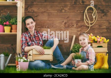 Nettes Kind Mädchen hilft ihrer Mutter für Pflanzen zu kümmern. Mutter und ihre Tochter beschäftigten sich mit der Gartenarbeit im Hinterhof. Frühlingskonzept, Natur und Pflege. Stockfoto