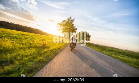 Dunkle Motorradfahrer Reiten High Power Motorrad in der Natur mit schönen Sonnenuntergang Licht. Reisen und Transport. Freiheit beim Motorradfahren Stockfoto