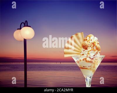 Sommernacht im Cafe an der Strandpromenade mit Eisbecher und Schlagsahne, Amaretti und Waffel Stockfoto