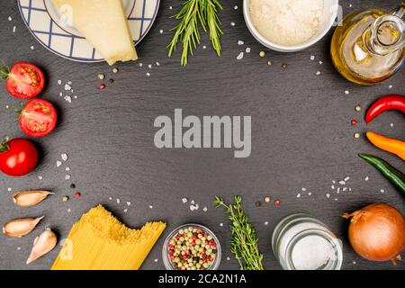 Spaghetti Napoli Zutaten auf einer Schieferplatte. Mit Thymian, Rosmarin, Zwiebel, Paprika, groben Salzkörnern, bunten Pfefferkörnern, Knoblauchzehen, Parmesan. Stockfoto