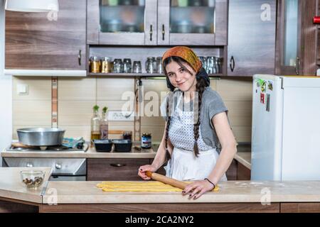 Lächelndes Mädchen in Schürze knetet Teig in der Küche, um sich für Ostern vorzubereiten Stockfoto
