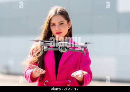 Starten Sie die Drohne, starten von Hand. Verschwommene junge Frau im Hintergrund, Fokus auf den Quadcopter Stockfoto