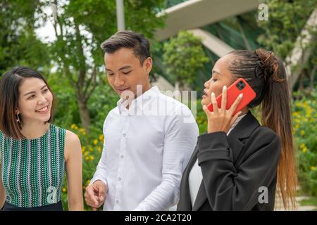 Geschäftstreffen im Freien. Drei Asiaten, ein Mann und zwei Frauen. Stockfoto