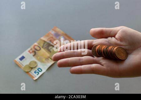 Euro-Münzen in junge Frau Hand.Banknote und mehr Münzen auf der Rückseite, isoliert grauen Hintergrund.Sparen Geld und Finanzkrise Konzept. Stockfoto