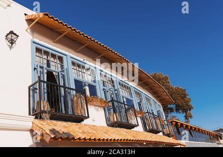 mediterranes Café am Meer mit weißen Wänden, wunderschönen dunkelblauen Holztüren und hellblauen Fenstern in der untergehenden Sonne. Sommerurlaub. Reisekonzept. Stockfoto
