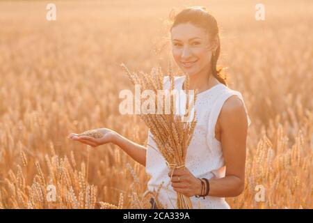 Frau hält Garbe Weizenohren auf dem landwirtschaftlichen Feld Stockfoto