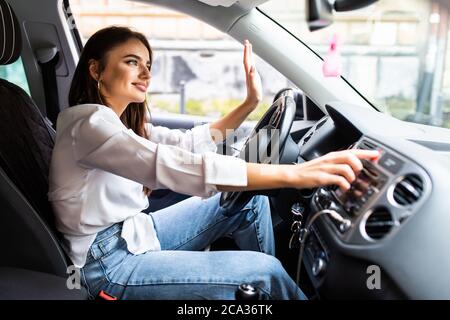 Frau drückt den Nottaster auf dem Armaturenbrett des Autos Stockfoto