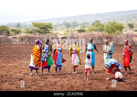 Maasai Frauen mit Kindern, in traditioneller Kleidung, in einem maasai Dorf. Maasai Mara National Reserve. Kenia. Afrika. Stockfoto