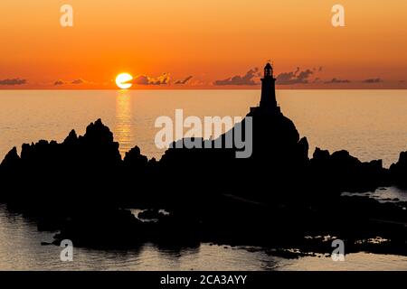 Corbiere Lighthouse auf der Insel Jersey, silhouetted gegen einen Sonnenuntergang Himmel Stockfoto