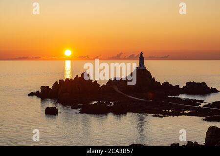 Corbiere Lighthouse auf der Insel Jersey, silhouetted gegen einen Sonnenuntergang Himmel Stockfoto