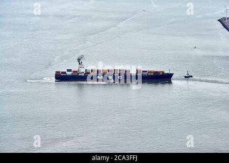 Ein Containerschiff, das von zwei Schleppern in der Mündung des Flusses Mersey, Liverpool Port, Großbritannien, manouvered wird Stockfoto