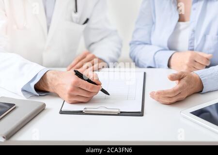 Arzt, der der Patientin vor der Behandlung Dokumente vorzeigt Stockfoto