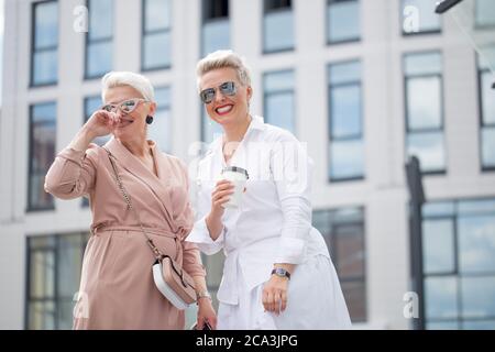 Porträt von zwei geschäftsfrauen außerhalb mit Kaffee mit Gebäuden auf Hintergrund Stockfoto