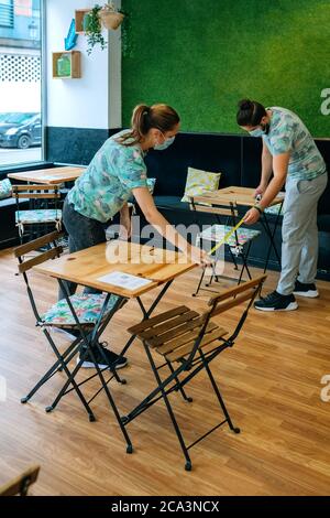 Arbeiter, die die soziale Distanz zwischen Tischen messen Stockfoto