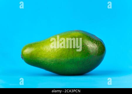 Reife frische grüne Avocado auf blauem Hintergrund Stockfoto