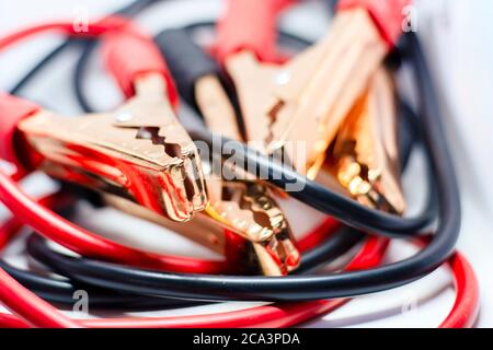 Nahaufnahme des roten und schwarzen Autobatterie-Jumper-Kabels, isoliert auf weißem Hintergrund. Ladekabel. Konzentrieren Sie sich auf Metall Stockfoto