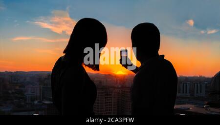 Paar fotografieren den wunderschönen Sonnenuntergang mit Blick auf die Stadt Stockfoto