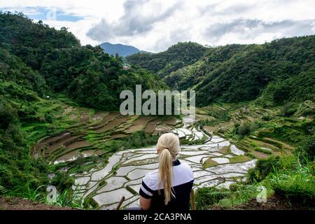Alleinreisende und blonde Frau genießen Blick auf Reisfelder in den Bergen in Asien. Foto aufgenommen in Banaue, Philippinen Stockfoto