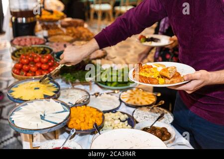 Mann, der das Essen vom Frühstückstisch im Restaurant nahm Stockfoto