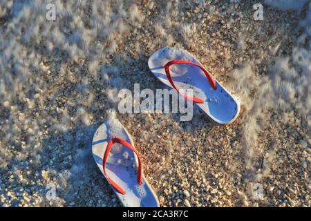 Gestreifte Flip-Flops im Meer schwimmen in klaren blauen Meerwasser. Exotische Urlaubs- und Reisezielszeniken mit Kopierplatz. Stockfoto