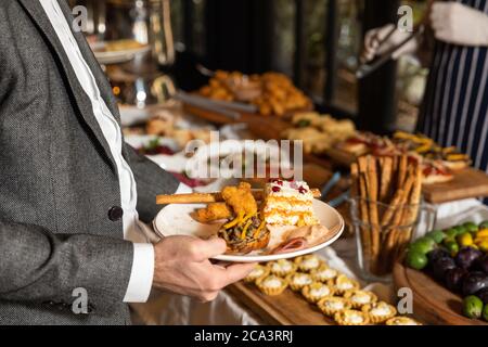 Mann, der das Essen vom Frühstückstisch im Restaurant nahm Stockfoto