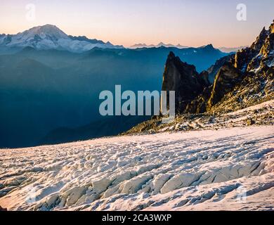 Dies sind die Berge der Arolla Alpen in der Schweiz, die auf der alten Jäger-Hochgebirgshandelsroute zwischen der französischen Stadt Chamonix und der Schweizer Stadt Zermatt gesehen und überquert werden. Dies ist die Szene von der Cabane d'Orney Blick über den Tour Gletscher auf den entfernten Gipfel des Grand Combin und die näher steilen Klippen der Clochers du Portalet ein beliebter Ort für Base-Jumping Fallschirmflieger. Stockfoto