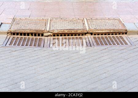 Quadratische Kanalentwässerung Kühlergrill auf der Straße Bordstein mit Fußgänger Gehwege. Stockfoto