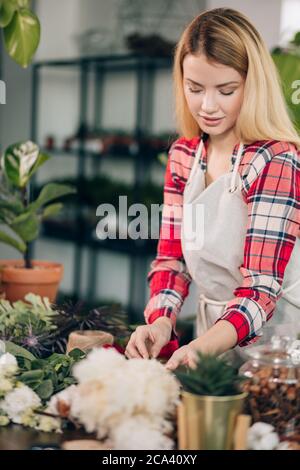 Menschen, Geschäft, Verkauf und Floristik Konzept. Junge kaukasische Frau Floristin, Kleinunternehmen Besitzer Überprüfung ihrer frischen Blumen und Pflanzen Vorräte. Einnahme Stockfoto